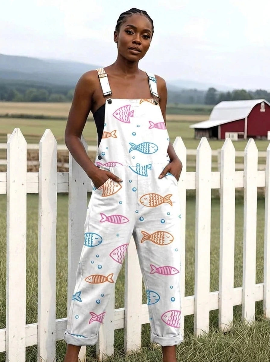 Woman in a white fish print jumpsuit standing by a white picket fence