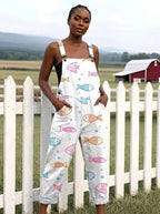 Woman in a white fish print jumpsuit standing by a white picket fence