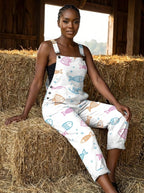 Woman in a white fish print jumpsuit sitting on hay bales