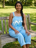 Woman wearing a light-blue heart print sleeveless overall jumpsuit sitting on a park bench