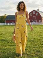 Woman walking in a farm field wearing a honeybee floral print jumpsuit