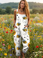 Woman wearing a white honeybee print sleeveless button-down overall jumpsuit standing in a flower field