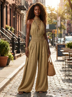 Woman wearing a khaki smocked-waist wide-leg palazzo jumpsuit on a sunny city street