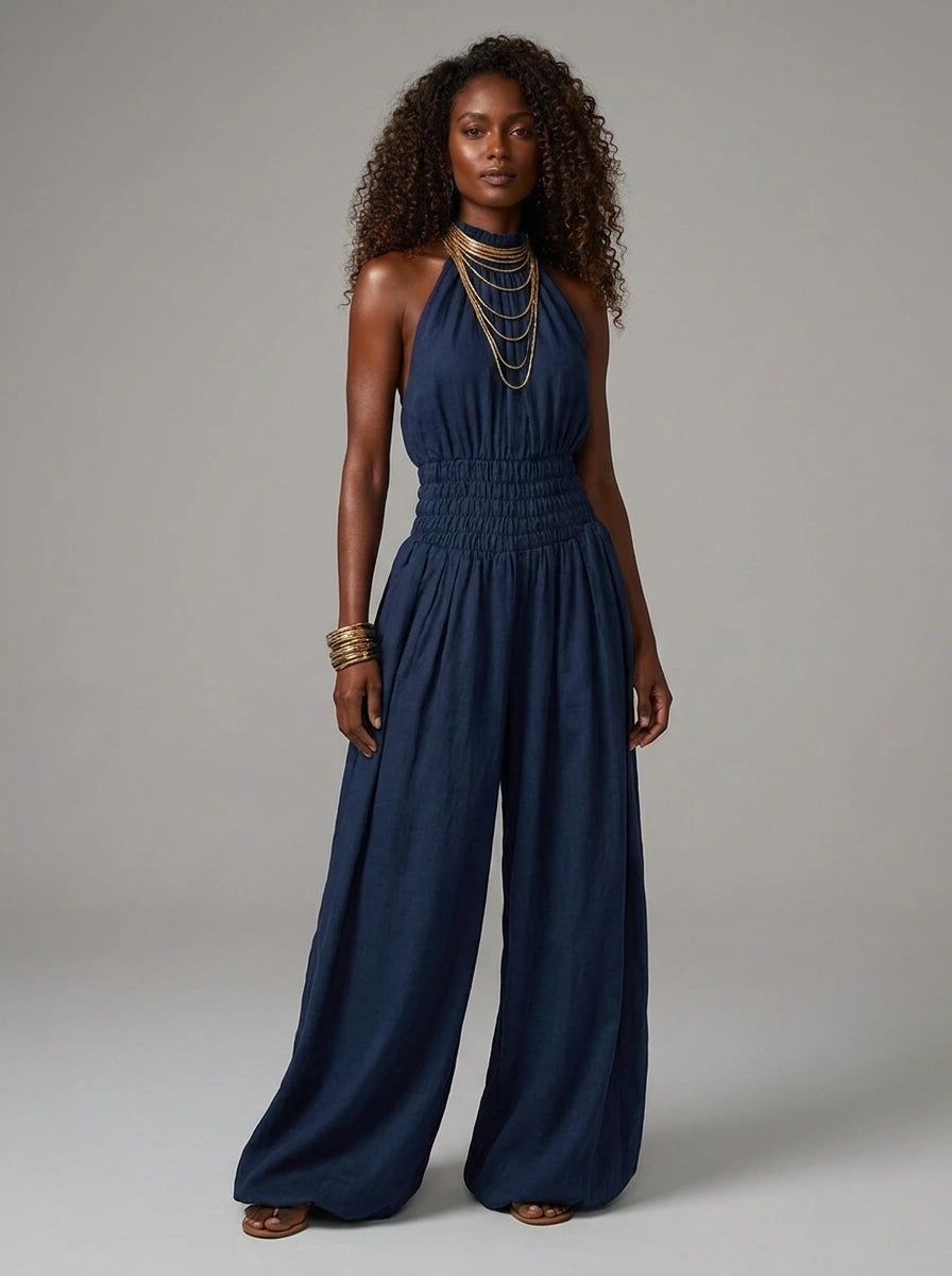 Woman wearing a navy blue smocked-waist wide-leg palazzo jumpsuit in a studio setting