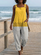 Woman wearing a yellow polka dot color-block sleeveless overall jumpsuit standing on a wooden beach boardwalk