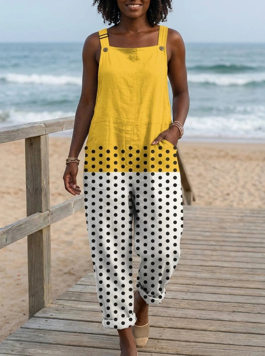 Woman wearing a yellow polka dot color-block sleeveless overall jumpsuit standing on a wooden beach boardwalk
