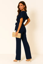 Woman wearing a dark blue ponte knit batwing jumpsuit - studio photo