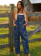 Woman standing near a wooden fence gate wearing a printed tie-waist jumpsuit