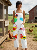 Woman wearing a white colorful rooster and bird print sleeveless wide-leg overall jumpsuit near a chicken coop
