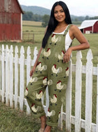 Woman wearing an olive-green rooster print wide-leg overall jumpsuit leaning against a white picket fence