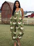 Woman wearing an olive-green rooster print wide-leg overall jumpsuit standing in a farm setting with a red barn