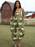 Woman wearing an olive-green rooster print wide-leg overall jumpsuit standing in a farm setting with a red barn