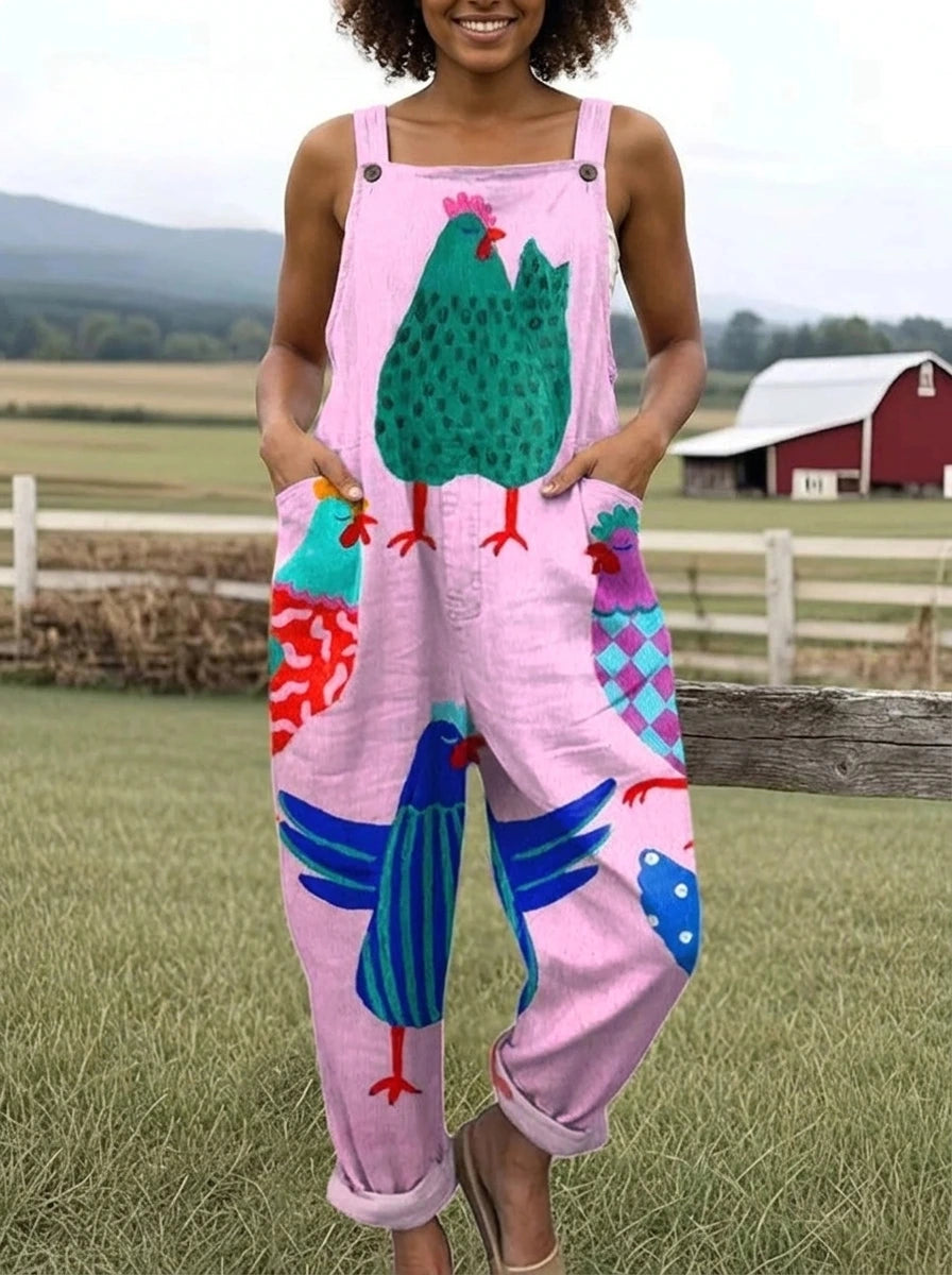 Woman wearing a pink colorful rooster print sleeveless wide-leg overall jumpsuit standing in a farm setting