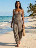 Woman wearing a grey ruffle strap harem jumpsuit on a tropical beach
