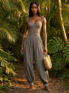 Woman wearing a grey ruffle strap harem jumpsuit in a tropical garden