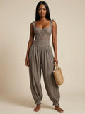 Woman wearing a grey ruffle strap harem jumpsuit in a studio setting