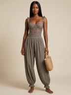 Woman wearing a grey ruffle strap harem jumpsuit in a studio setting