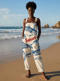 Woman wearing a cream jumpsuit with a blue sardine fish print on the beach