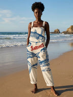 Woman wearing a cream jumpsuit with a blue sardine fish print on the beach