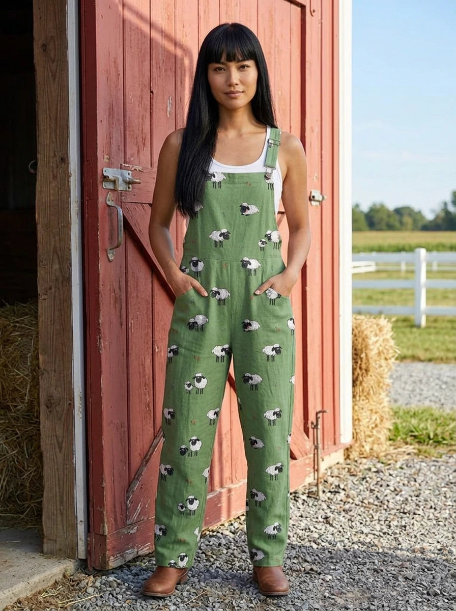 Woman in a green sheep print jumpsuit standing by a red barn door
