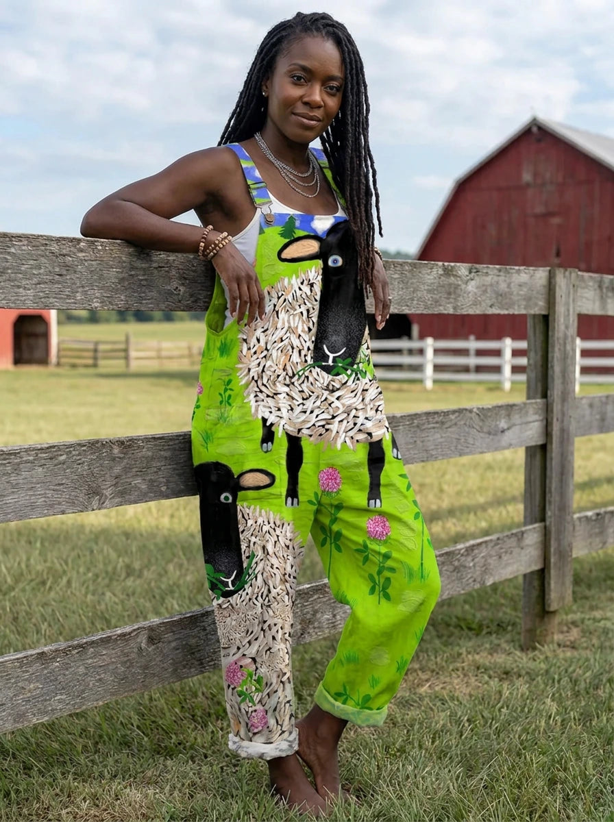 Woman wearing a green sheep and floral print sleeveless wide-leg overall jumpsuit leaning against a wooden farm fence