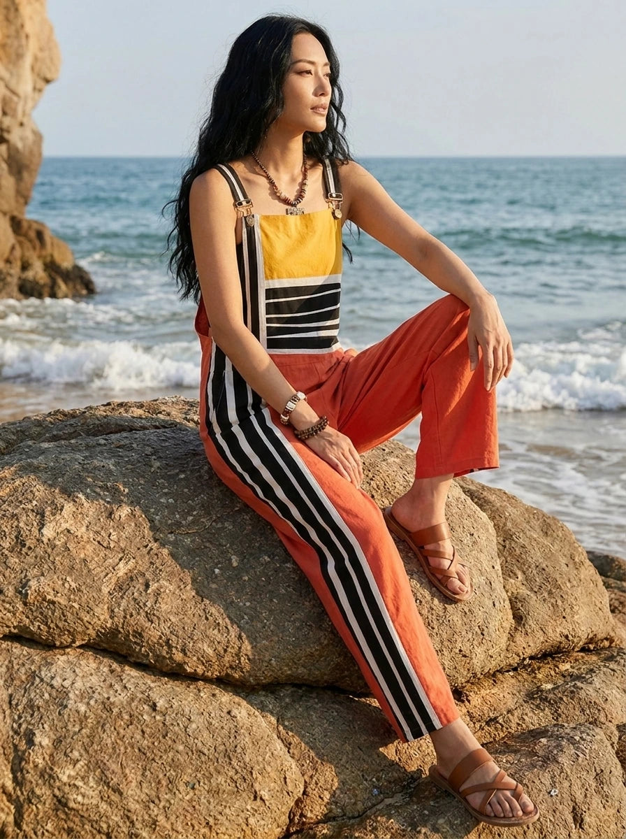 Woman sitting on a large beach rock wearing a striped color-block jumpsuit
