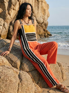 Woman standing on beach rocks wearing a striped color-block jumpsuit