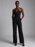 Woman wearing a black strapless tuxedo jumpsuit, studio photo, standing pose