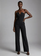 Woman wearing a black strapless tuxedo jumpsuit, studio photo, hand on hip pose