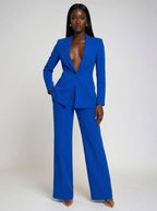 Woman wearing a blue stretch crepe two-piece jumpsuit, studio photo, hand in pocket pose