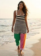 Woman in a striped color-block jumpsuit walking along the beach shoreline