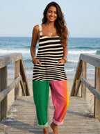 Woman in a striped color-block jumpsuit standing on a wooden beach boardwalk