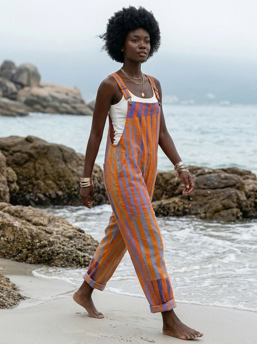 Woman walking along the shoreline wearing a sunset print jumpsuit