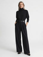 Black elegant casual jumpsuit with relaxed fit, turtleneck, wide-leg trousers, and matching black belt, studio front view.