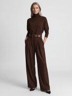 Brown elegant casual jumpsuit with relaxed fit, turtleneck, wide-leg trousers, and matching belt, studio front view.