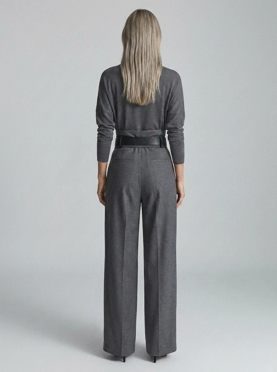 Grey elegant casual jumpsuit, back view, showing turtleneck and belted waist.