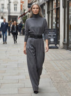 Grey elegant casual jumpsuit with relaxed fit, turtleneck, and wide-leg trousers, worn outdoors on an urban street.