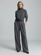 Grey elegant casual jumpsuit with relaxed fit, turtleneck, wide-leg trousers, and matching black belt, studio front view.