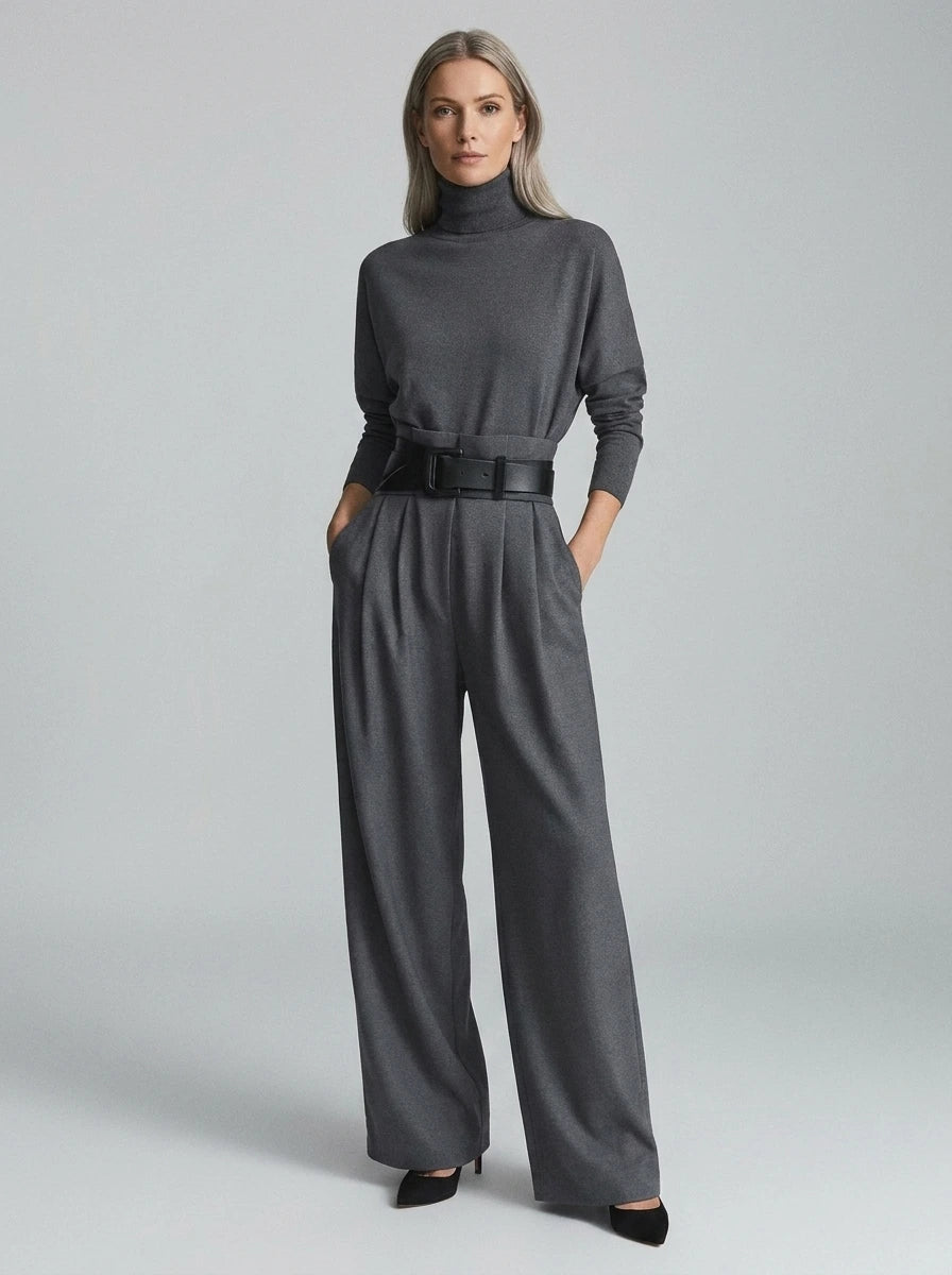 Grey elegant casual jumpsuit with relaxed fit, turtleneck, wide-leg trousers, and matching black belt, studio front view.