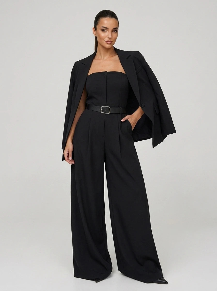 Woman wearing a black wide-leg jumpsuit with matching blazer, studio shot