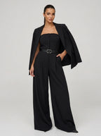 Woman wearing a black wide-leg jumpsuit with matching blazer, studio shot