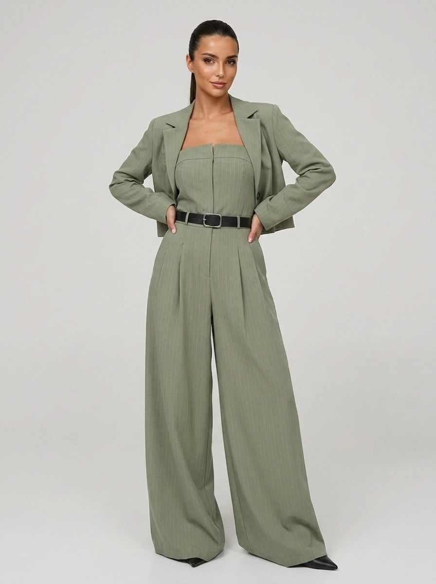Woman wearing a green wide-leg jumpsuit with matching cropped blazer, studio shot