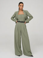 Woman wearing a green wide-leg jumpsuit with matching cropped blazer, studio shot