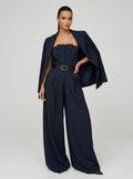 Woman wearing a navy pinstripe wide-leg jumpsuit with matching blazer, studio shot