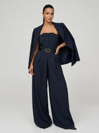 Woman wearing a navy pinstripe wide-leg jumpsuit with matching blazer, studio shot