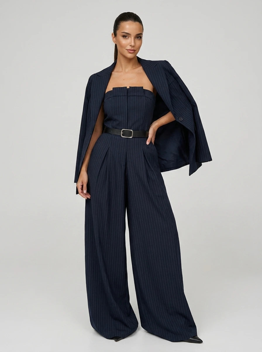 Woman wearing a navy pinstripe wide-leg jumpsuit with matching blazer, studio shot
