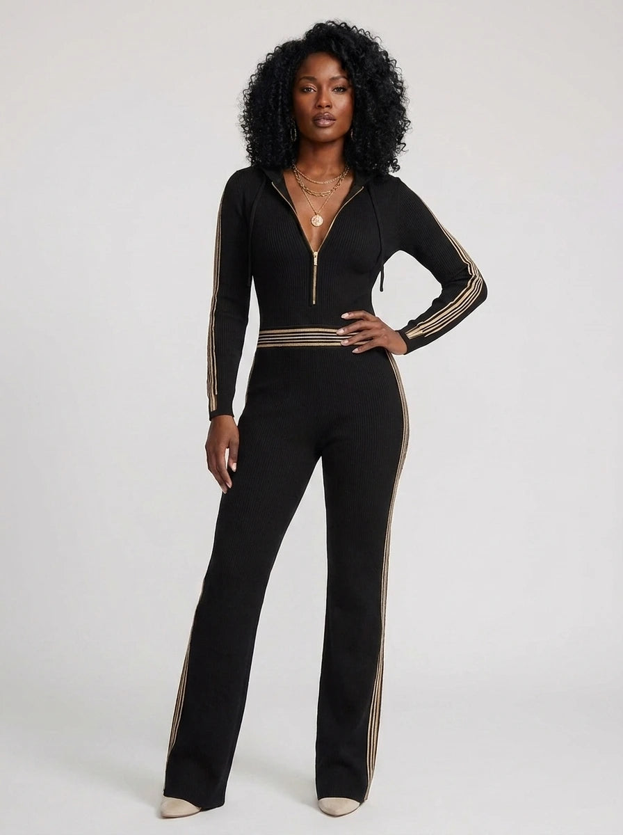 Woman wearing a black knit zip-front jumpsuit with hood and sporty stripes, studio shot
