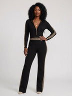 Woman wearing a black knit zip-front jumpsuit with hood and sporty stripes, studio shot