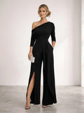 Driftly black asymmetrical one-shoulder jumpsuit with crossed detail and flowing wide-leg trousers, in a minimalist studio setting with soft window light.