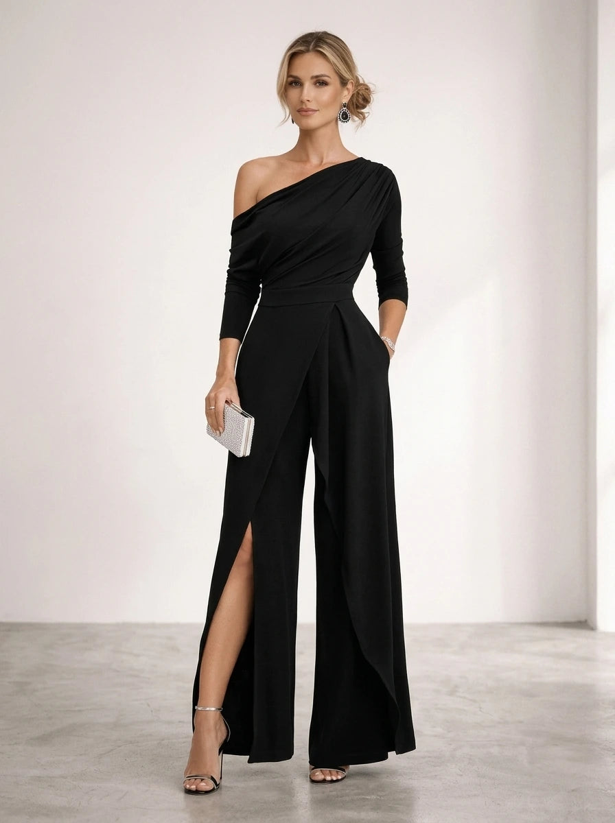 Driftly black asymmetrical one-shoulder jumpsuit with crossed detail and flowing wide-leg trousers, in a minimalist studio setting with soft window light.